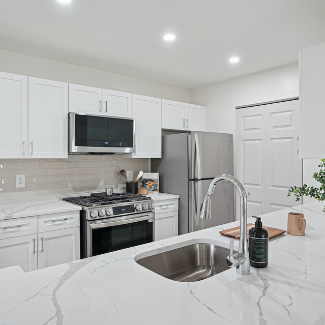 The Estates - Modern White Kitchen With Island And Sink